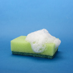 Close-up of a green soapy sponge on blue background