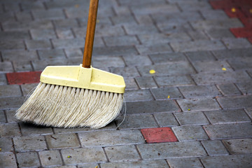 broom cleans paving slabs