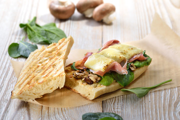 Heißes Sandwich aus dem Grill mit feinem Serrano Schinken, Pilze und jungem Spinat mit Käse überbacken  - Street food: Toasted panini with Spanish ham and spinach leaves topped with grated cheese