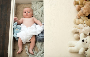 Newborn toddler with peaceful face lies on soft knitted blankets