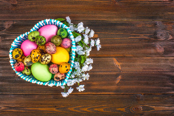 Quail multi-colored Easter eggs on a brown wooden table.