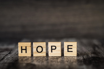 the word hope is made of bright wood cubes with black letters on a dark wooden background