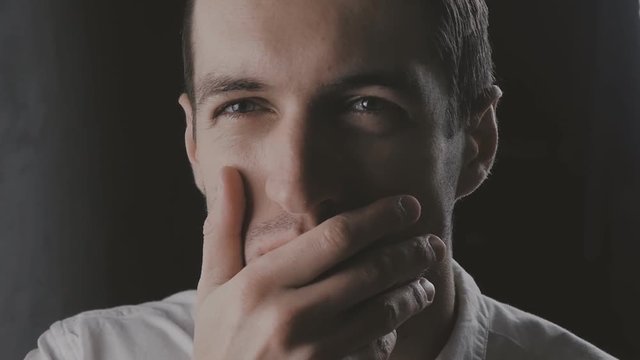 Closeup Skeptical Man standing on black background looking forward with disappointment in slowmotion. Facial emotions