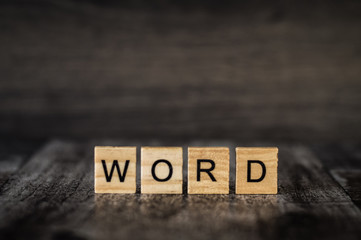 the word "word" is made of bright wood cubes with black letters on a dark wooden background
