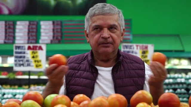 Man Choosing and Showing Tomatoes at Supermarket