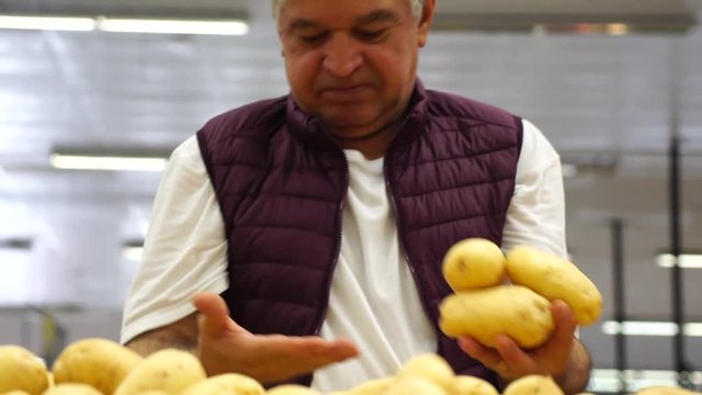 Man Choosing and Showing Potato at Supermarket