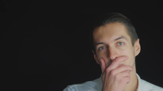 Closeup Skeptical Man standing on black background looking forward with disappointment in slowmotion. Facial emotions
