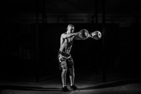 A strong man picks up kettlebell in gym. Kettlebell lifting. Black and white conception