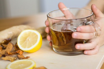 Kid's hands holding a cup of home made healthy sugarfree drink made from dried fruits, with lemon...