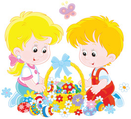Little children with a decorated Easter basket of colorfully painted eggs and flowers