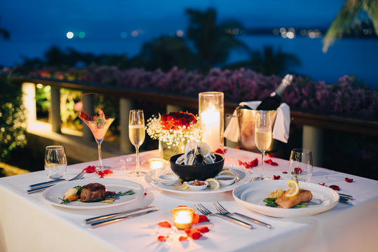 Romantic candlelight dinner luxury table setup for couple with beautiful light as background. Glasses of champagne and beautiful food presentation on table.. Concept for valentine's day  and date.
