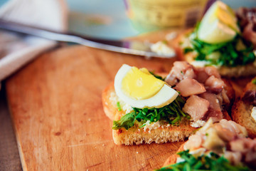 bruschetta, appetizer, canapes: fish tuna and spinach on toast of white bread, with egg on wooden Board