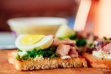 bruschetta, appetizer, canapes: fish tuna and spinach on toast of white bread, with egg on wooden Board
