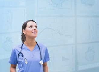 Nurse looking up against blue digital background