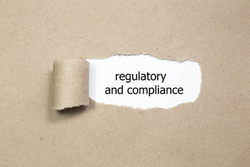 The text regulatory and compliance appearing behind torn paper