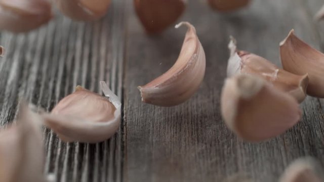 Cloves of garlic falling and rolling on a table. Shot with high speed camera, phantom flex 4K. Slow Motion.