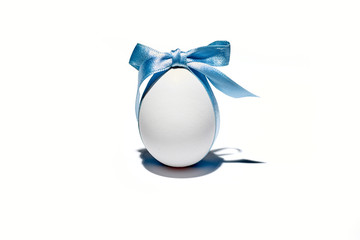Uovo con fioccho azzurro a celebrare la pasqua su fondo bianco