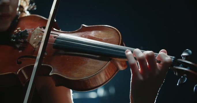 detail shot, performance of violinist girl on stage, light, dark background