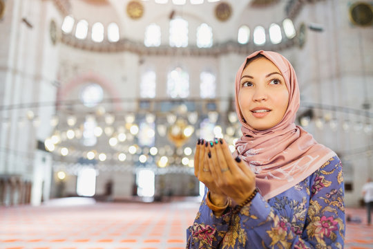 Young pretty muslim woman praying inside the mosque