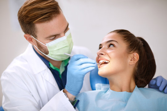 Dentist examine girl’s teeth with mirror