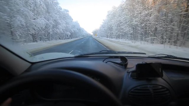 The young man slowly driving a car on a winter road. In winter, the majority of motorists still goes slow down and be careful.
