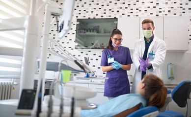 Dentist with assistant talking with patient in dental chair