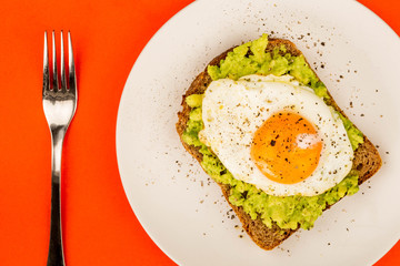 Fried Egg Sunny Side Up on Crushed Avocado And Rye Bread Open Faced Sandwich