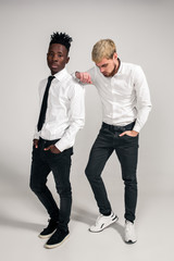 Friends. Two guys in white shirts and dark pants posing in the studio on a white background