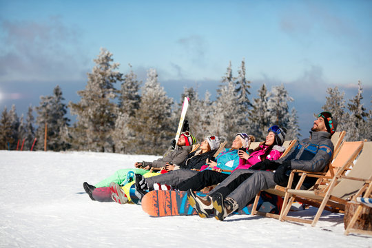 friends skiers relax in chairs on the mountain top