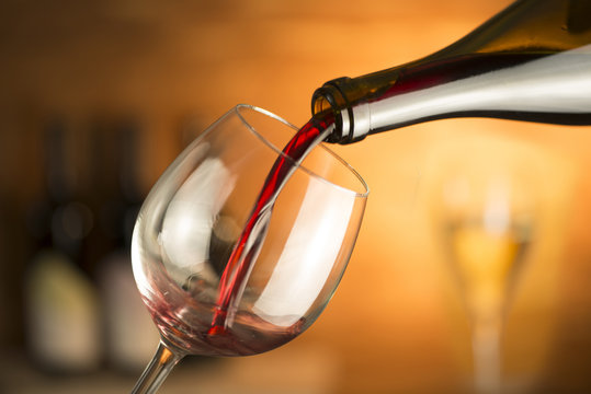 bottle pours red wine into a glass