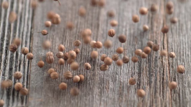 Falling coriander seeds on wooden table. Shot with high speed camera, phantom flex 4K. Slow Motion.