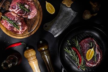 Fresh raw meat. Beef Tenderloin and marbled beef steaks on grill pan and frying board with seasoning, black background top view.
