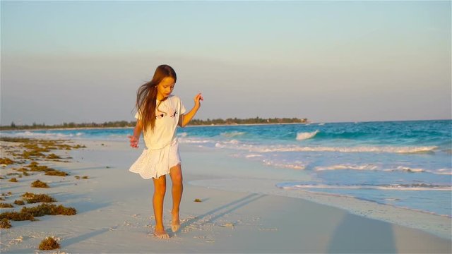 Active little girl at beach having a lot of fun. Sporty kid dancing on the seashore