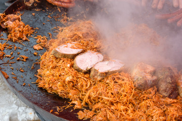 Cabbage fried with meat in frying pan on the street