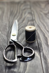 On a black wooden stench, close-up, scissors spool of thread with a needle.