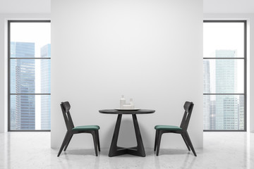 Round table and green and black chairs, windows