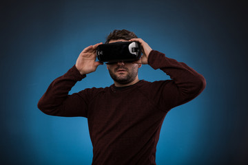 Young man with virtual reality headset or 3d glasses over blue  backgroun,Studio shot.guy with a beard