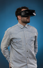 Man wearing virtual reality goggles. Studio shot, blue  backgroun.texas shirt
