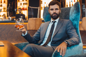 Businessman sitting in a business center bar drinking alcohol confident