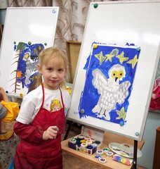 Little girl standing with her drawing on an easel