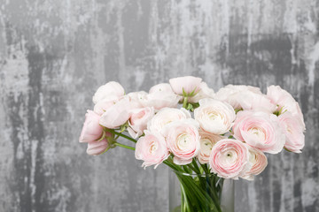 Vase with beautiful bouquet of ranunculus flowers on wooden table. rustic background with copy space. Close up Persian buttercup flower.