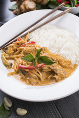 Thai Red curry served with white rice in a white plate with chopsticks