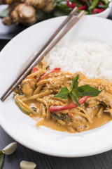 Thai Red curry served with white rice in a white plate with chopsticks