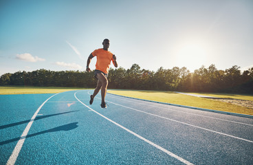 Fit young athlete sprinting down an outdoor track