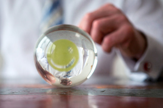 man holding paper with smiley face in front of glass ball