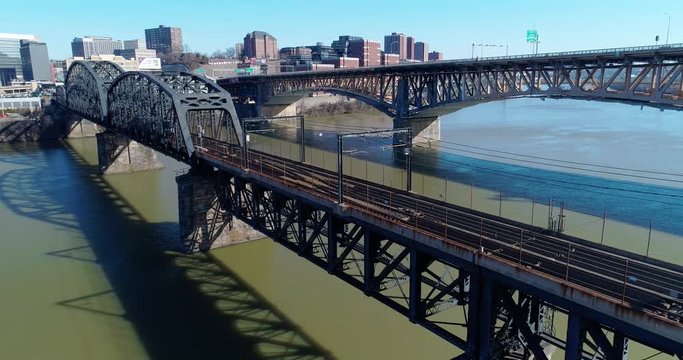 A slow reverse aerial view of subway cars traveling on a railroad bridge over the Monongahela River in downtown Pittsburgh, PA.  	