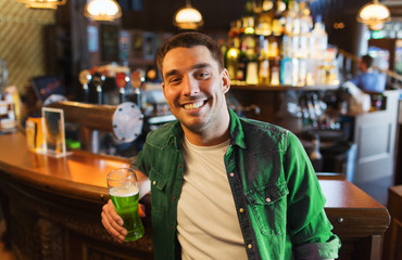 man drinking green beer at bar or pub