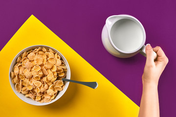 Food, healthy eating, people and diet concept - close up of woman eating muesli with milk for breakfast over purple and yellow background