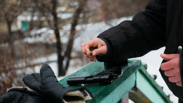 Man checking starting gun outdoor, get out bullet and put it in magazine body back