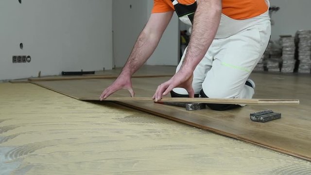 worker joining parket floor. slow motion